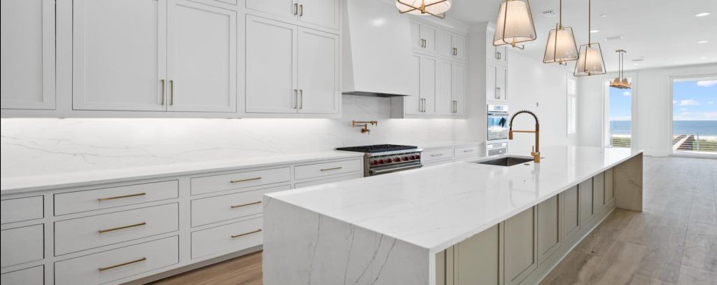 interior kitchen with white cabinets featuring gold accents, and marble island.